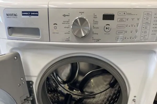 A close-up of the control panel and open door of a white Maytag front-load washer.
